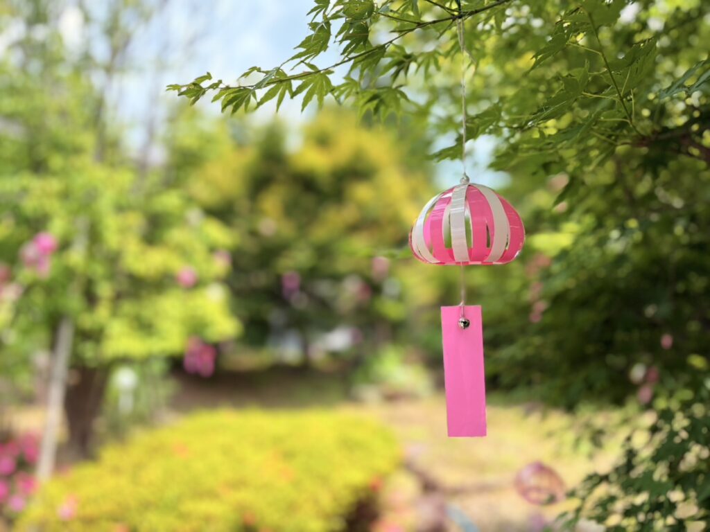 青もみじに吊るされたピンクの風鈴飾り。