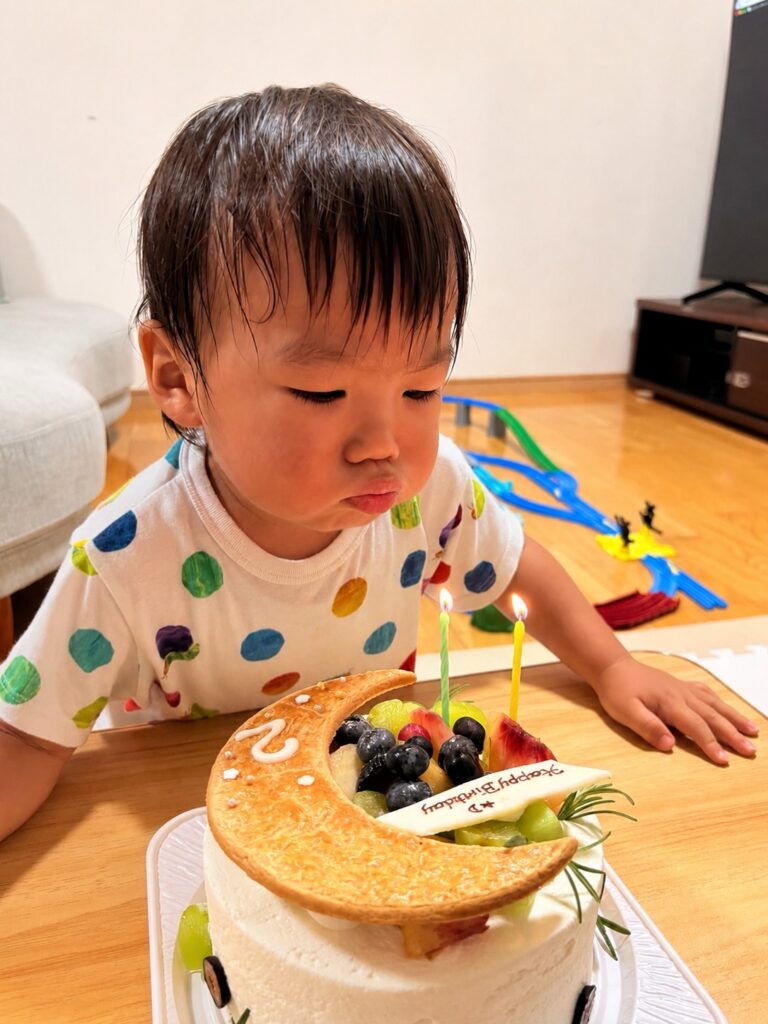 2歳の誕生日ケーキのローソクを吹き消す様子